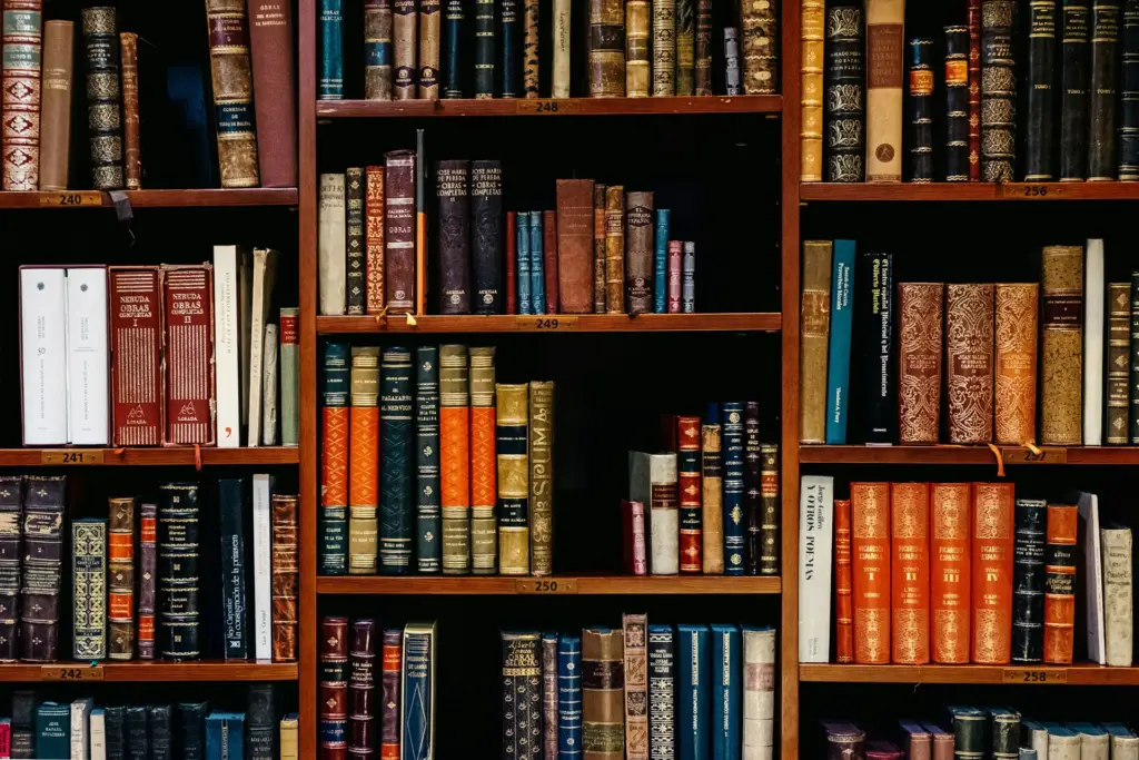 A close-up of a wooden bookshelf filled with various colorful hardback books.