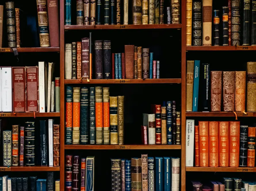 A close-up of a wooden bookshelf filled with various colorful hardback books.