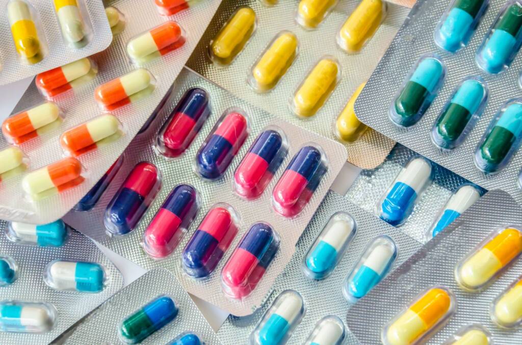 Various colorful capsules and pills in blister packs arranged closely.