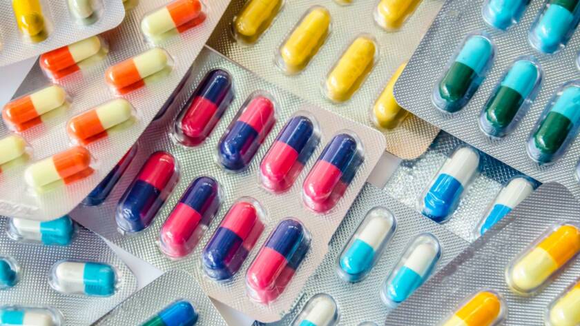 Various colorful capsules and pills in blister packs arranged closely.