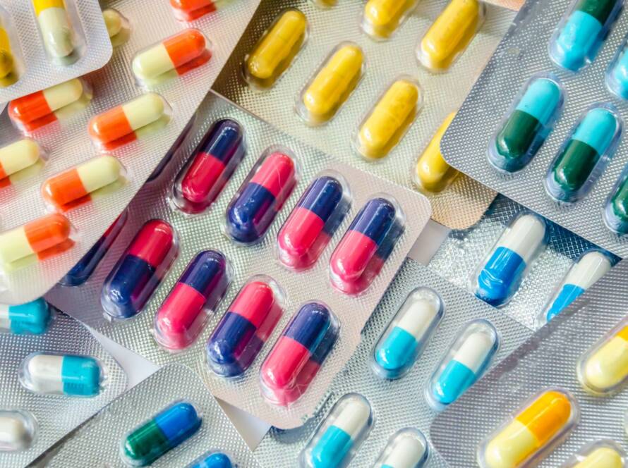 Various colorful capsules and pills in blister packs arranged closely.