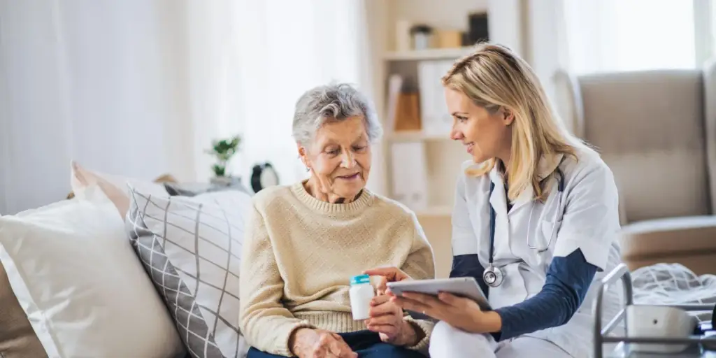 A caregiver assists an elderly woman with medication management.