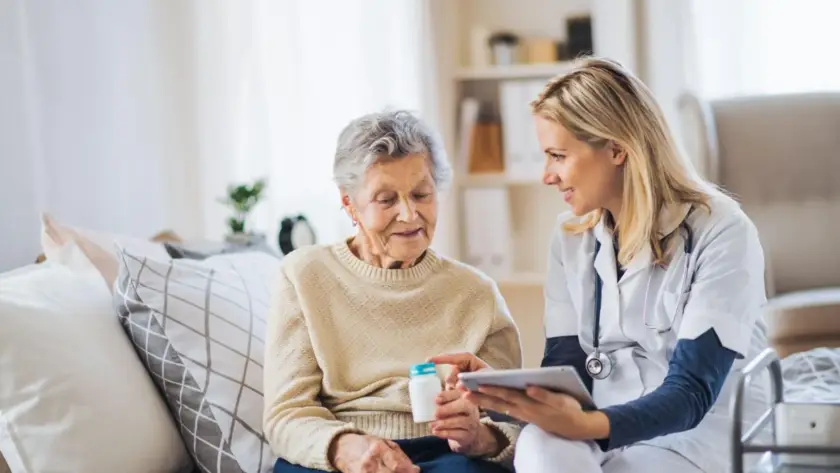A caregiver assists an elderly woman with medication management.
