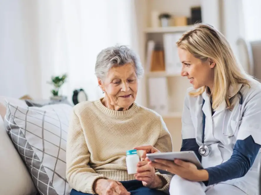 A caregiver assists an elderly woman with medication management.