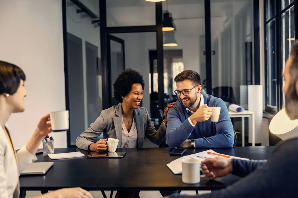 Colleagues sharing a light moment during a meeting in a modern office.
