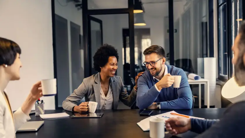 Colleagues sharing a light moment during a meeting in a modern office.