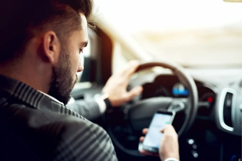 Man looking at phone while driving a car.