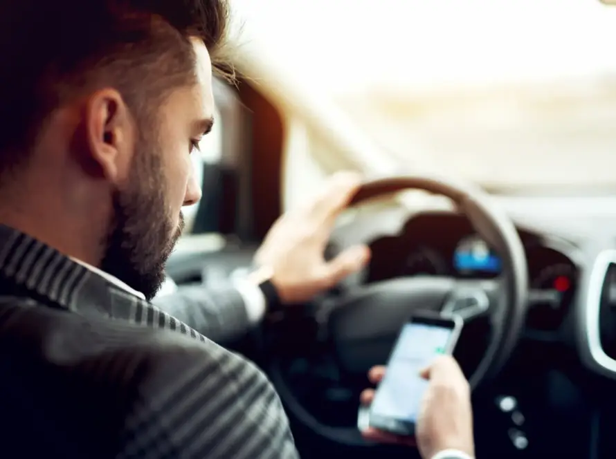 Man looking at phone while driving a car.