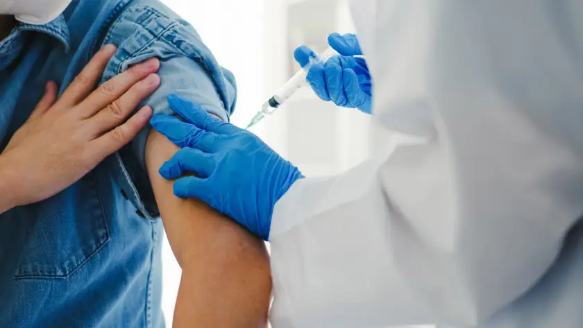 A healthcare worker administers a vaccine shot to a person's arm.