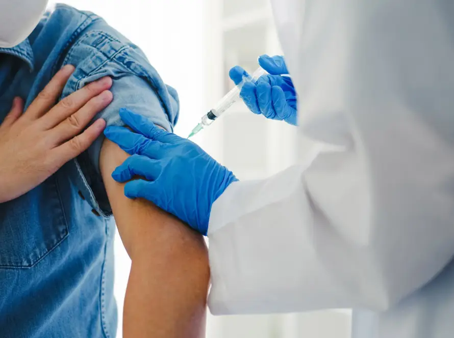 A healthcare worker administers a vaccine shot to a person's arm.