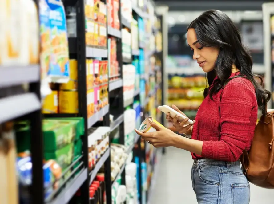 Woman reading a product label in a grocery store aisle.