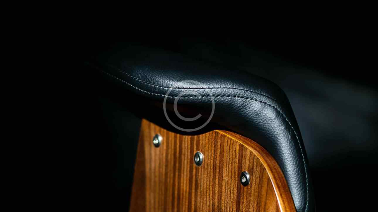 Close-up of a wooden chair with black leather upholstery and metal studs.