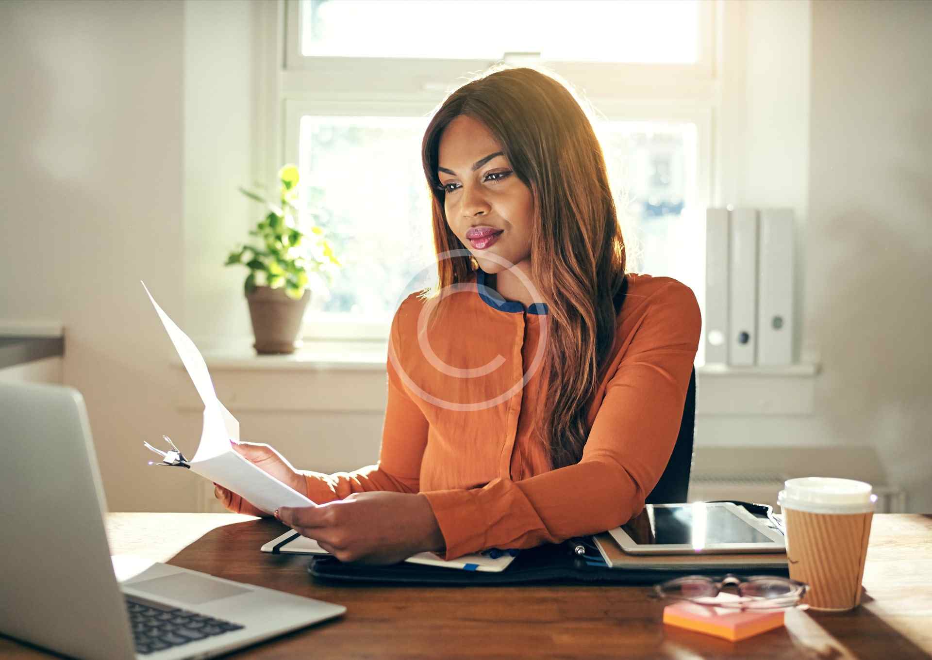 A woman happily working on her laptop in a cozy home office.