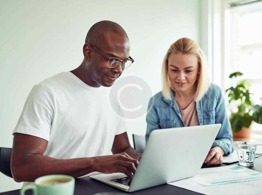 Two people happily working together on a laptop.