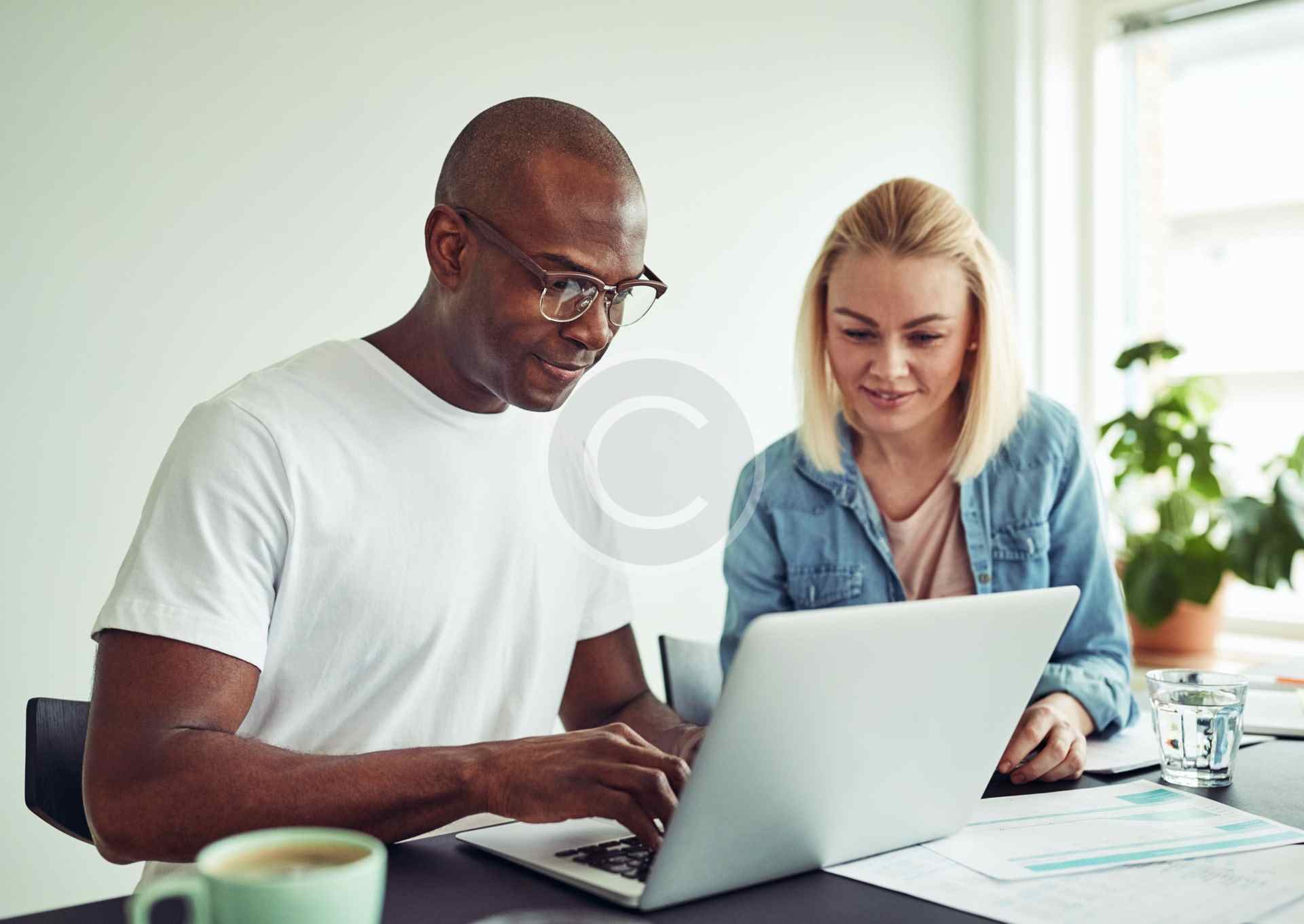 Two people happily working together on a laptop.