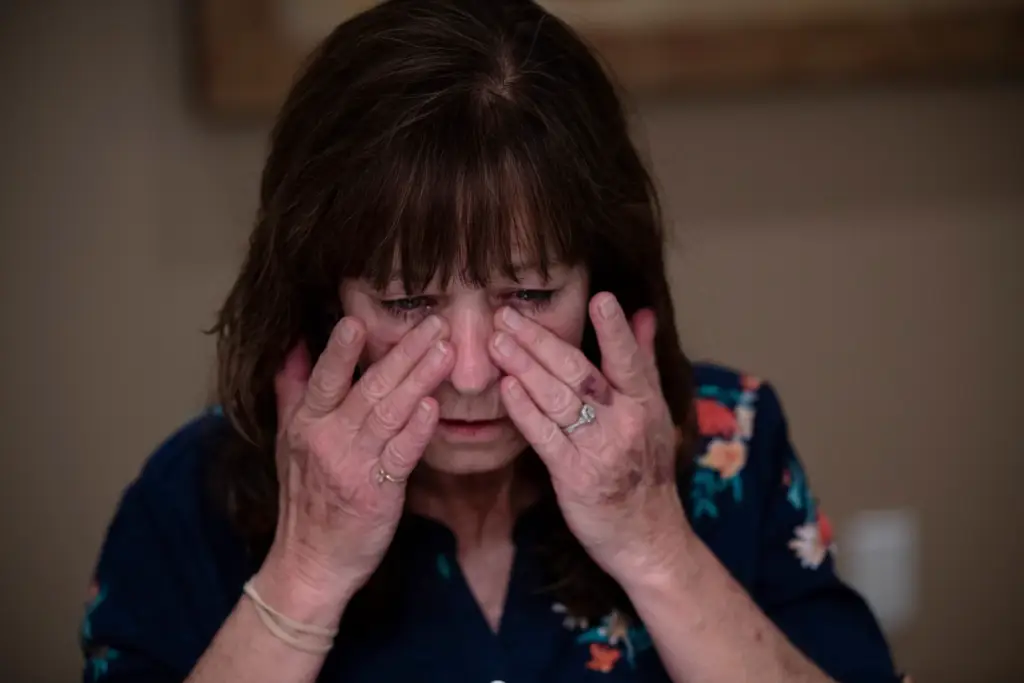 A woman rubbing her tired eyes indoors.