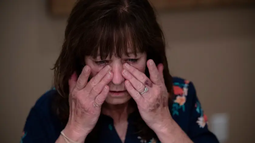 A woman rubbing her tired eyes indoors.