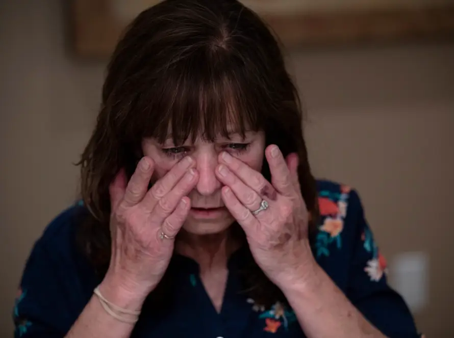 A woman rubbing her tired eyes indoors.