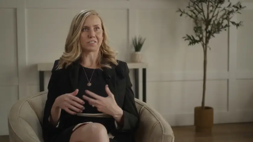 Woman speaking while seated in a cozy room.