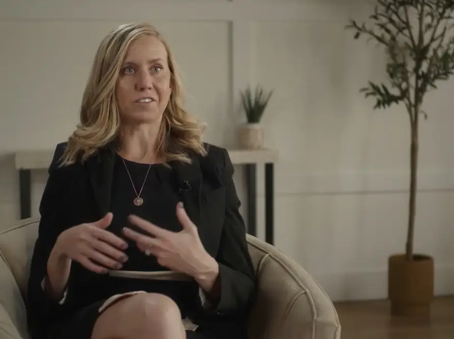 Woman speaking while seated in a cozy room.