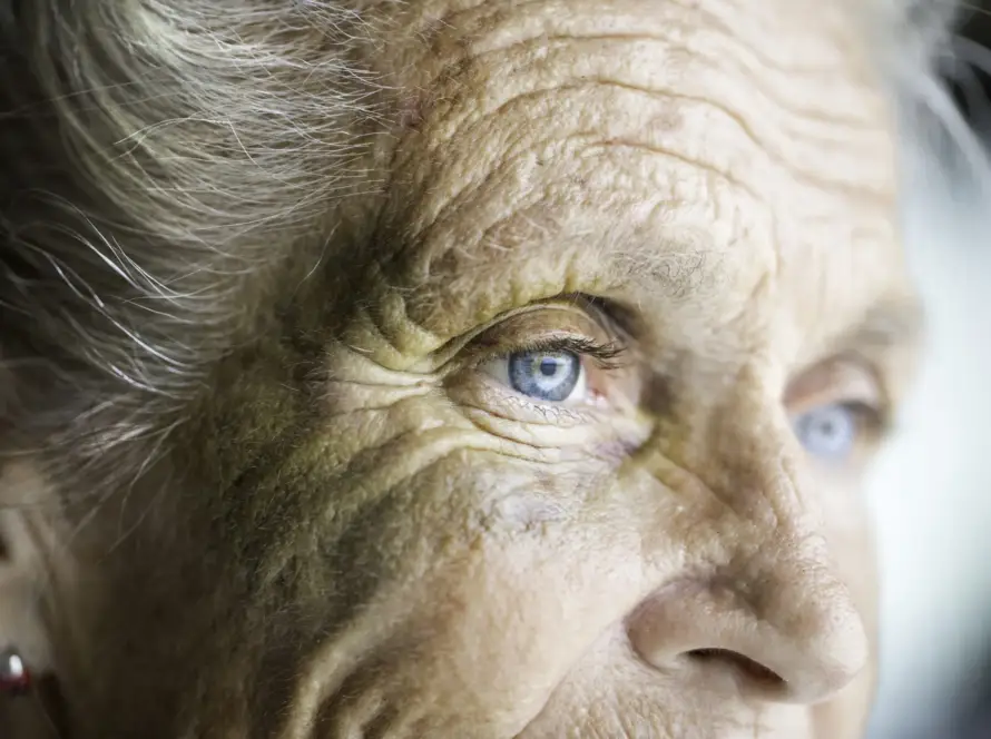 Close-up of an elderly person's face with blue eyes and wrinkles.