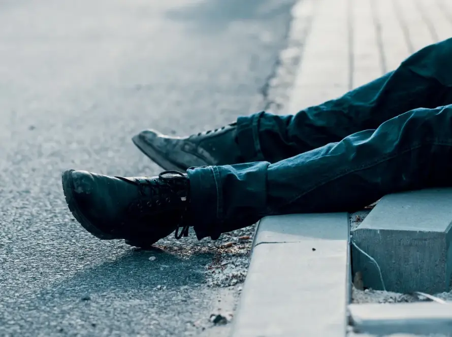 Person sitting on a curb with legs stretched out on the road.