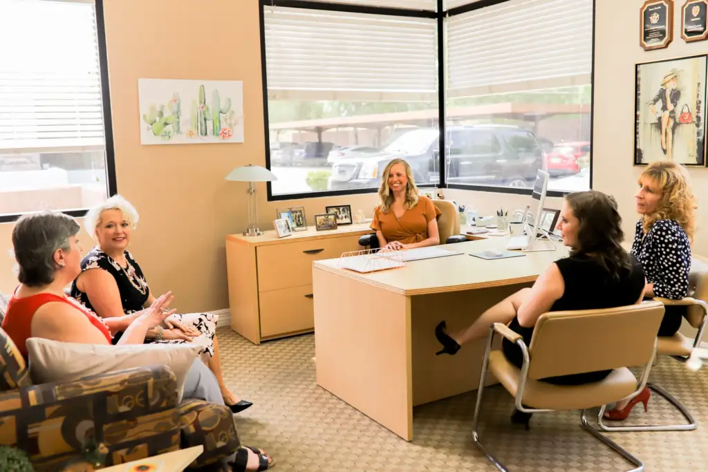 A group discussion in a bright office with four people seated.