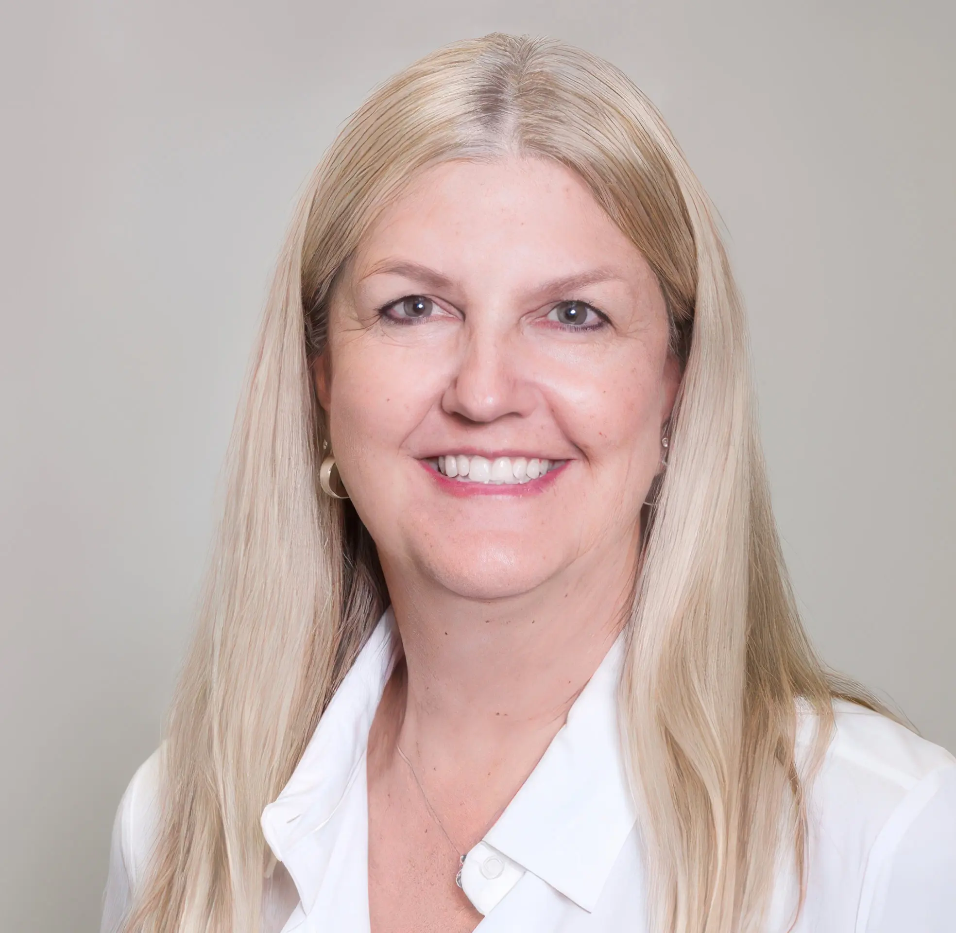 Smiling woman with long blonde hair in a white blouse.