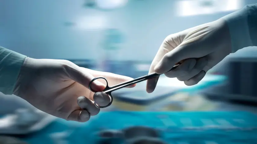 Surgeons exchanging a surgical instrument during an operation.