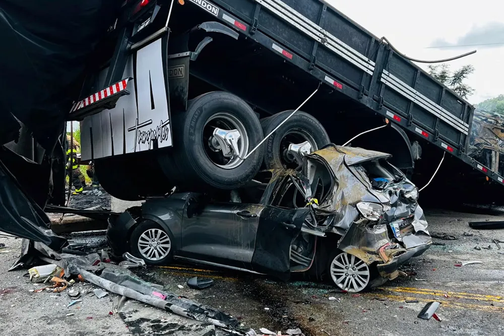 Severe accident with a truck crushing a car on a wet road.