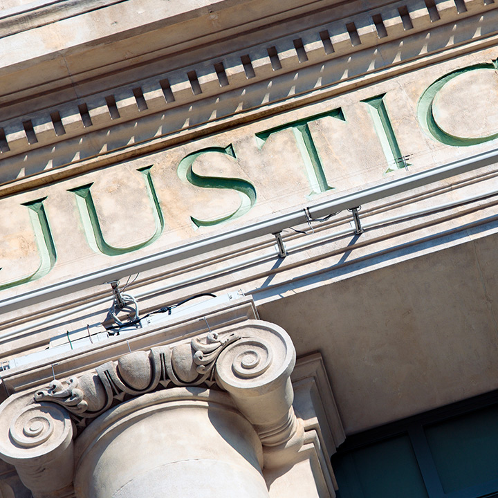 Close-up of 'JUSTICE' engraved on a classical courthouse facade.