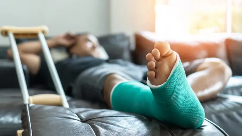 Person resting with a green cast on their foot, using crutches.