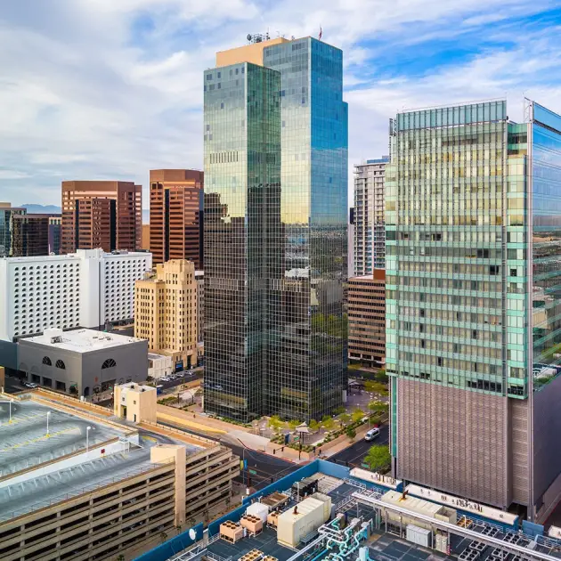 Modern city skyline with tall glass buildings under a blue sky.